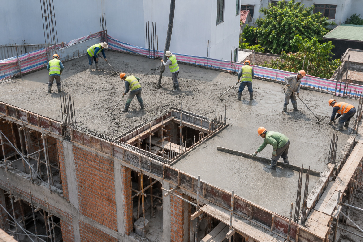 Đội thợ đổ và gạt bê tông sàn nhà phố nhìn từ trên cao